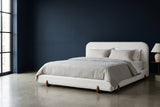 Fossacesia white textured fabric bed against a deep ink-navy wall in a Chicago loft, a tall black steel window at the left