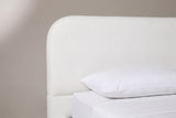 The upper corner of the Fossacesia headboard: a tall white textured panel with a large rounded top corner, a plain lower band and a white pillow