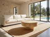 Fossano 31.5-Inch Round Burl Wood Veneer Pedestal Coffee Table on a jute rug in front of a linen sofa in a poolside villa