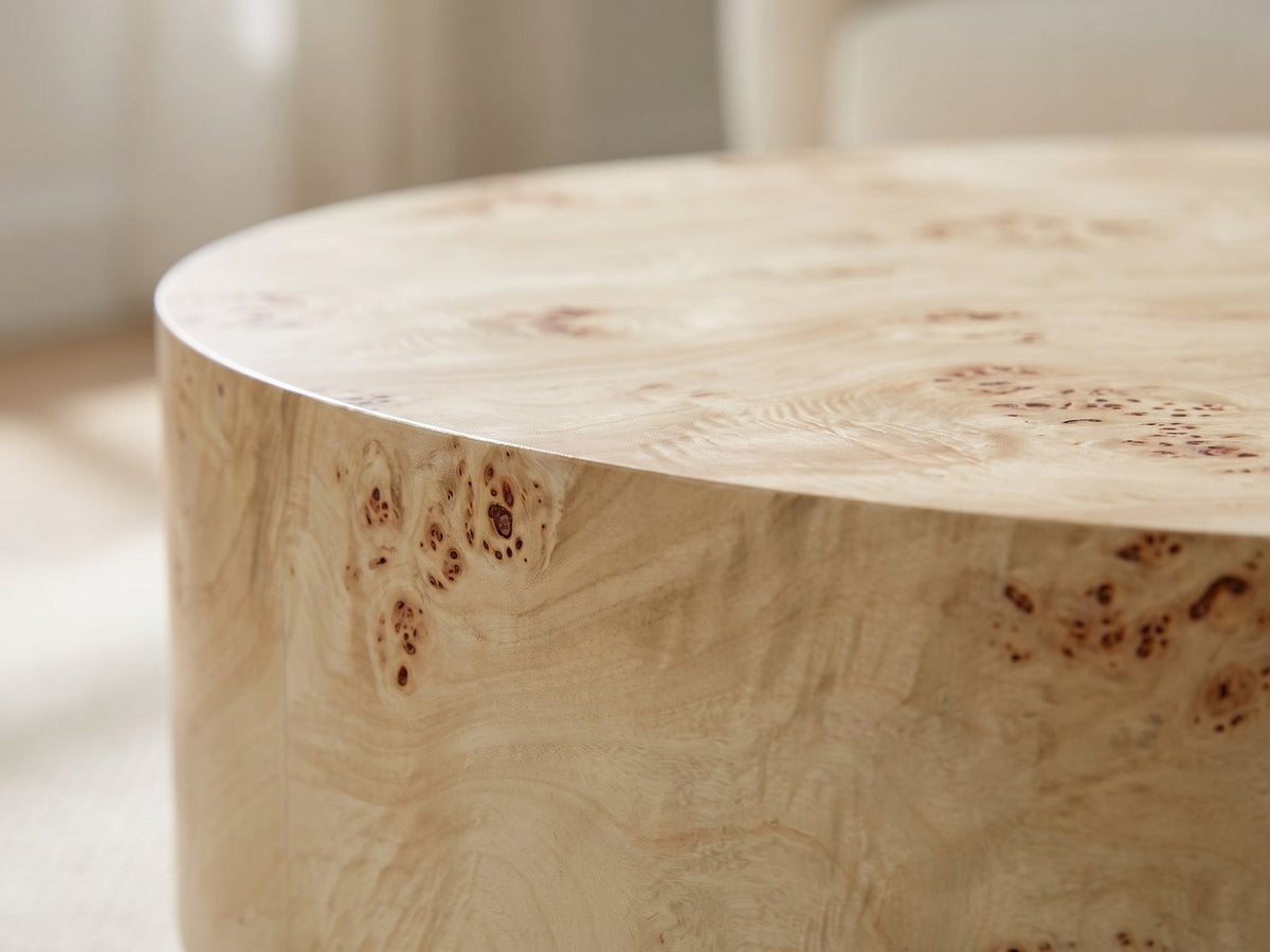 Close-up of the Fossano 31.5-Inch Round Burl Wood Veneer Pedestal Coffee Table: the crisp edge of the round top over the burl veneer drum