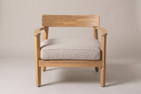 A Furnari club chair seen straight from the front: the curved back panel, two curved arms on the front legs and the deep beige seat cushion