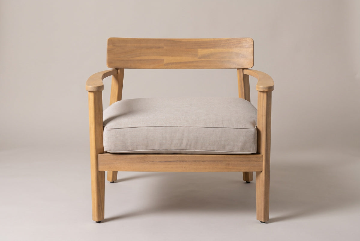 A Furnari club chair seen straight from the front: the curved back panel, two curved arms on the front legs and the deep beige seat cushion