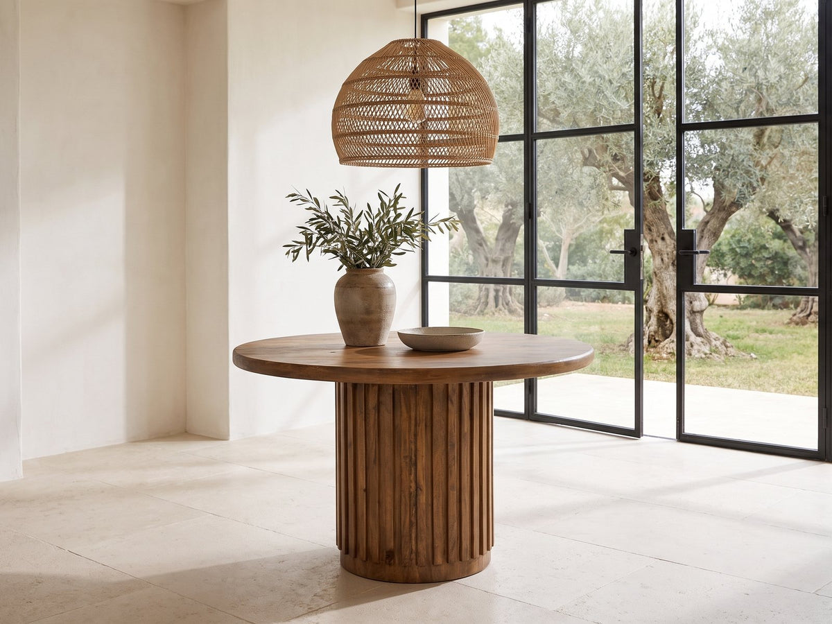 Fuscaldo 47-Inch Round Mango Wood Slatted Pedestal Dining Table in a sunlit villa dining area with olive trees outside