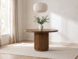 Fuscaldo 47-Inch Round Mango Wood Slatted Pedestal Dining Table in a bright plaster dining room with linen curtains