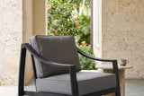 Galati black aluminum lounge chair in a Coral Gables loggia with coral stone walls, gray-green cement tiles and an arch onto a garden of palms and hibiscus (side table not included)