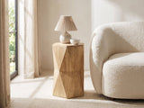 Gallicano Mango Faceted Hexagon Side Table with a lamp and a ceramic bowl beside a curved cream boucle seat in a bright plaster room