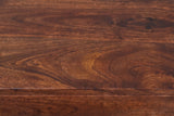 Close-up of the chestnut mango wood on the Galtelli nightstand: deep reddish brown swirling grain with amber patches running to a rounded edge