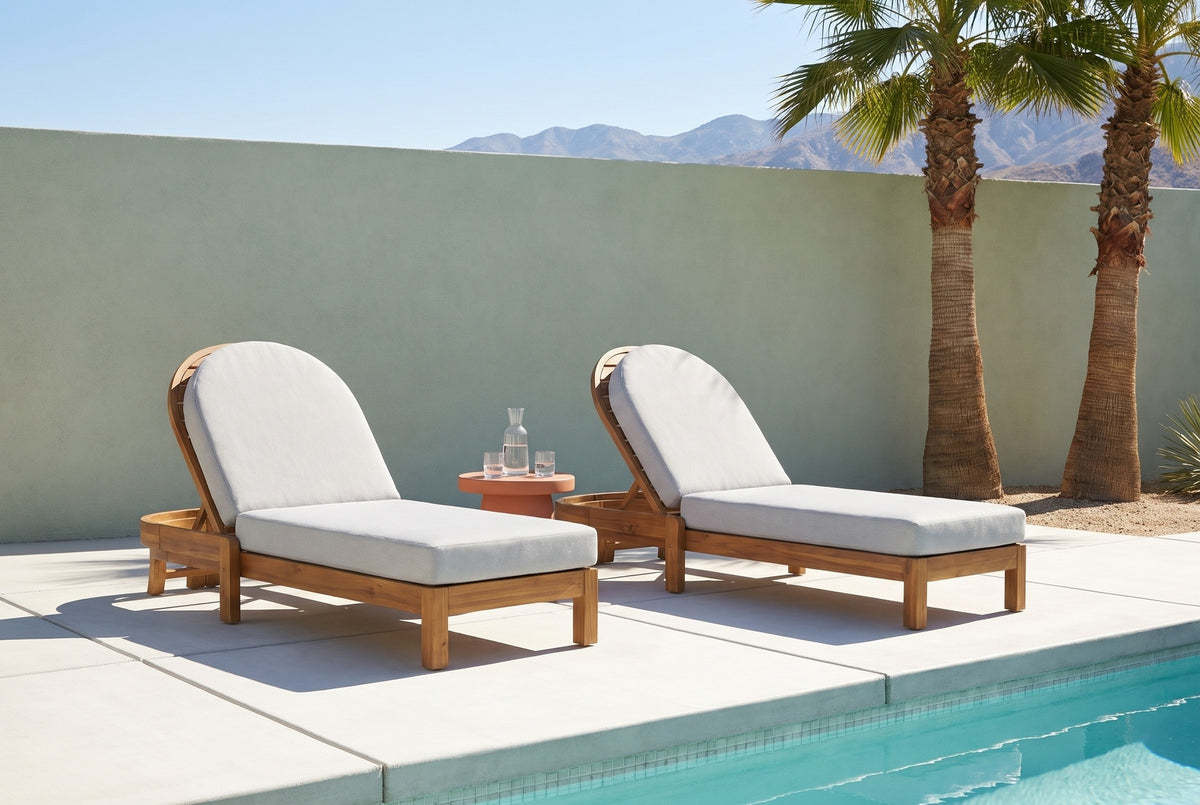 Two Gangi acacia chaise lounges on white concrete pavers by a pool in Palm Springs, a sage-green stucco wall, fan palms and mountains behind (side table not included)