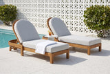 Two Gangi acacia chaise lounges on a terrazzo pool deck in Sarasota, a white breeze-block screen wall and sea grape behind (side table and towel not included)