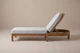 One Gangi chaise lounge from the side: the long low frame on square legs, the raised arched backrest and the curved head band