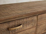 Close-up of the Gasperina Reclaimed Fir Four-Drawer Console Table: an antique-brass strap pull on a rough-sawn fir drawer front below the moulded top edge