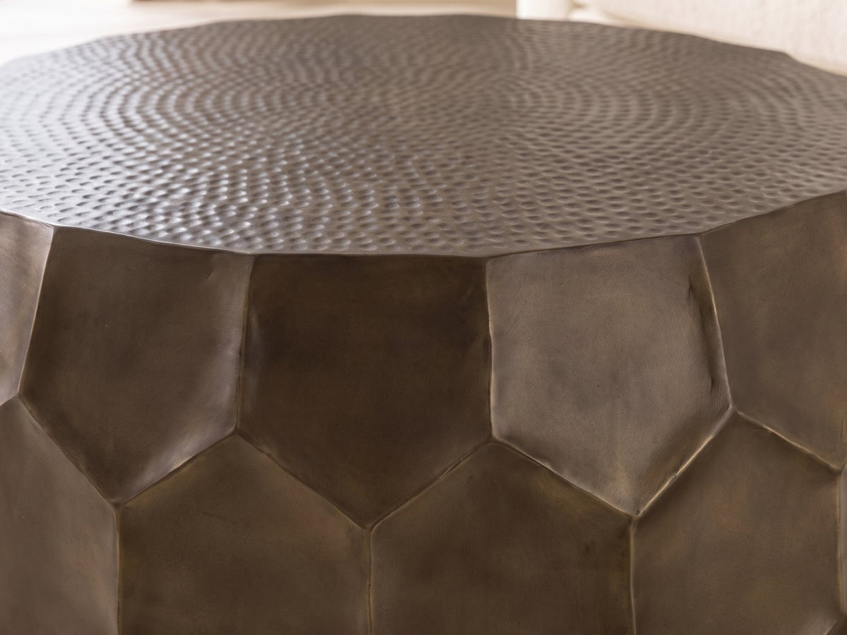Close-up of the Gavi 32-Inch Round Antique Bronze Faceted Aluminum Drum Coffee Table: the hammered top meeting the faceted hexagon panels