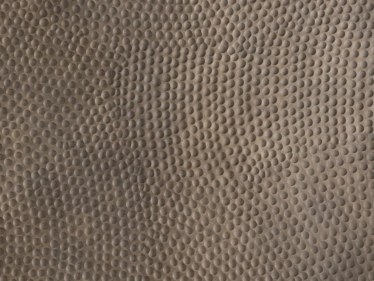 Close-up of the Gavi 32-Inch Round Antique Bronze Faceted Aluminum Drum Coffee Table: the hand-hammered top in antique bronze