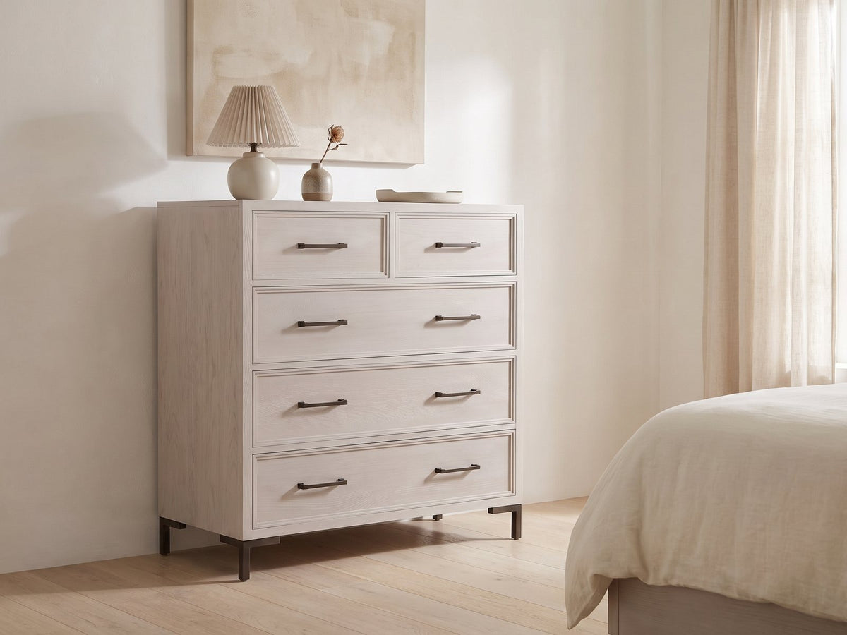 Gemona 41-Inch Cerused Oak 5-Drawer Chest against a plaster wall under an abstract canvas in a bright bedroom