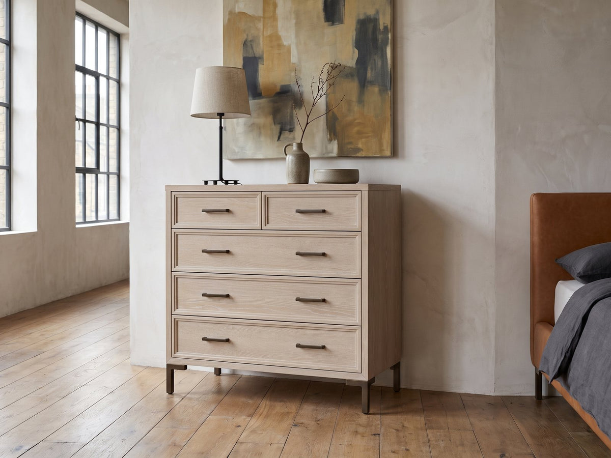 Gemona 41-Inch Cerused Oak 5-Drawer Chest against a plaster wall in an industrial loft bedroom