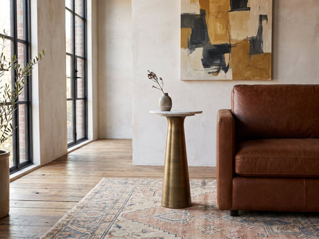 Genazzano White Marble Tapered Pedestal Side Table with a stoneware vase beside a cognac leather armchair in a sunlit loft