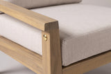 Close-up of the acacia on the Geraci chair: the flat arm rail and front post in a light teak finish with a brass-coloured bolt head, beside the beige seat cushion
