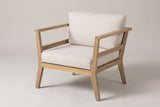 The Geraci acacia club chair with pale beige cushions, three-quarter view from the front on a light studio backdrop
