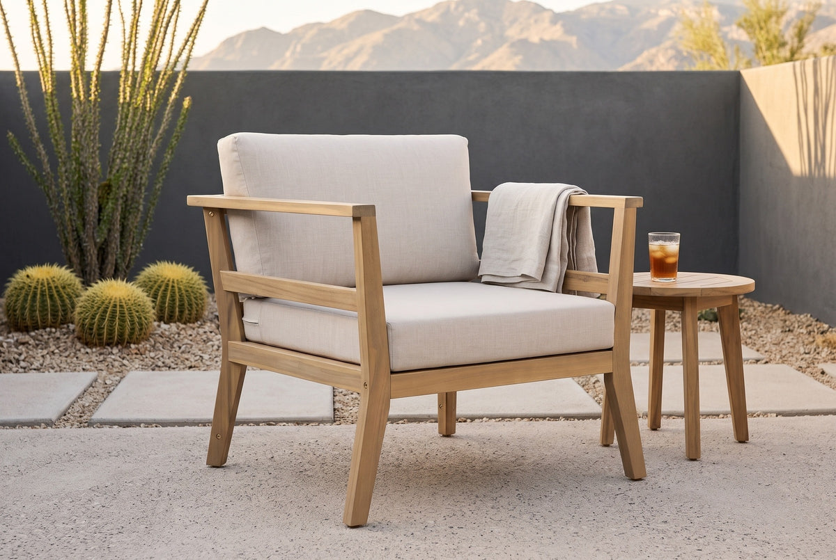 Geraci acacia club chair in a Tucson desert courtyard with a charcoal plaster wall, golden barrel cacti and mountains behind (side table and throw not included)