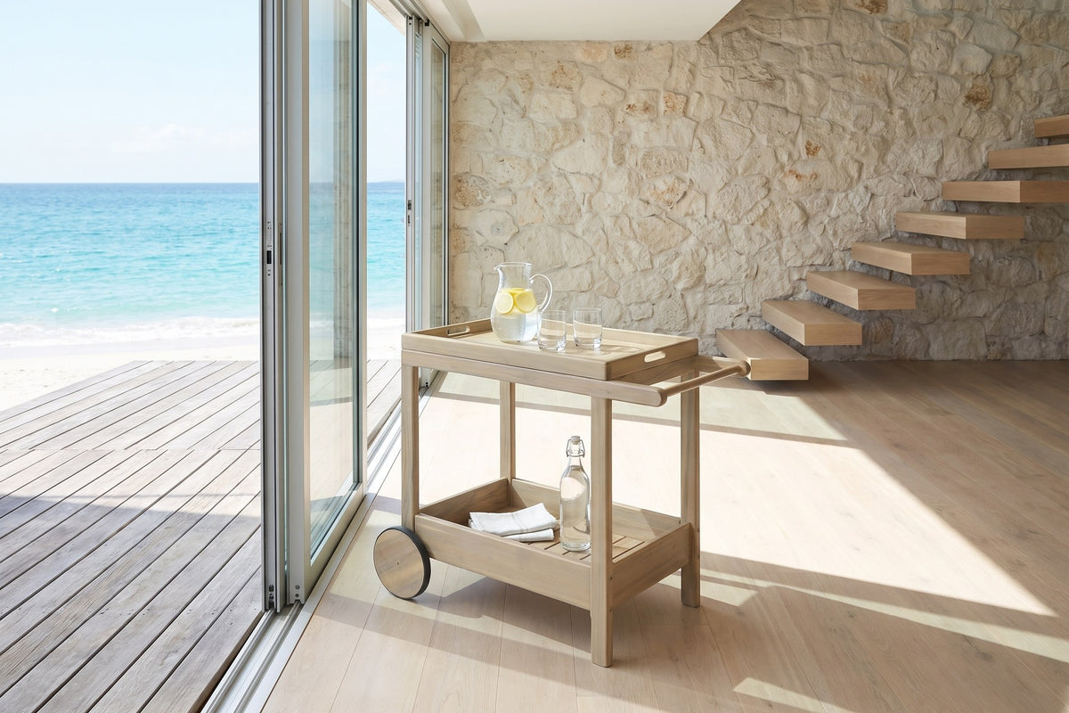 Gerocarne 36-Inch Acacia Wood Outdoor Rolling Bar Cart in an oceanfront glass house
