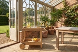 Gerocarne 36-Inch Acacia Wood Outdoor Rolling Bar Cart in an orangery