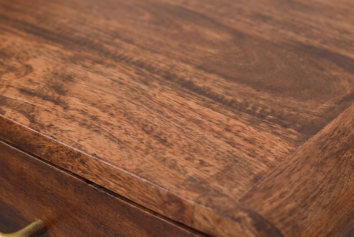 Close-up of the chestnut mango wood on the Ghilarza nightstand: reddish brown grain with darker streaks running to a rounded edge