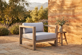 Giardini eucalyptus lounge chair on a sandstone terrace in an Ojai garden at golden hour, a rammed-earth wall, olive trees and lavender behind (stool and decor not included)