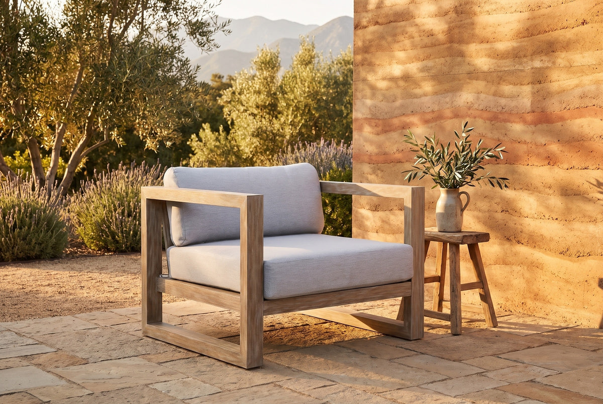 Giardini eucalyptus lounge chair on a sandstone terrace in an Ojai garden at golden hour, a rammed-earth wall, olive trees and lavender behind (stool and decor not included)