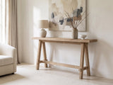 Ginosa Reclaimed Elm Trestle Console Table against a plaster wall under an abstract canvas in a bright living room