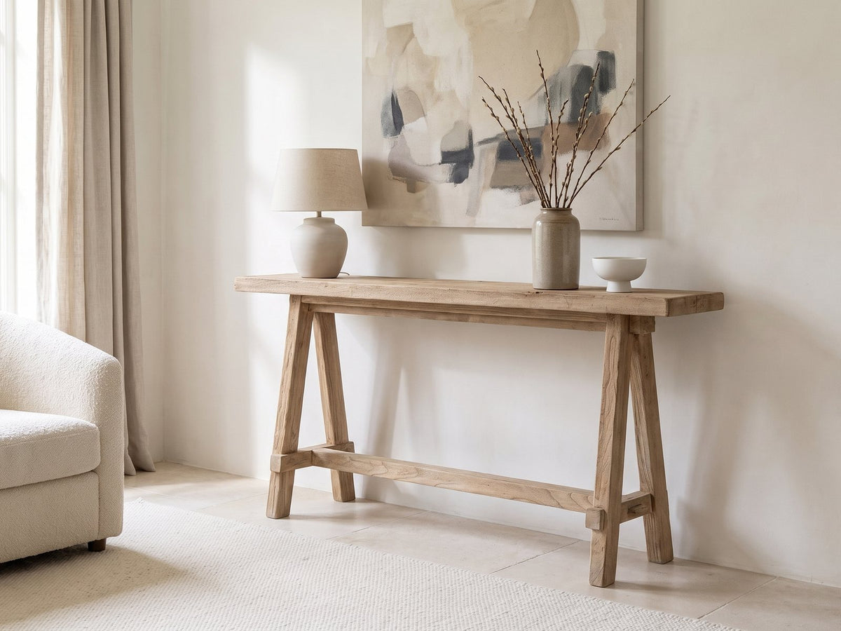 Ginosa Reclaimed Elm Trestle Console Table against a plaster wall under an abstract canvas in a bright living room