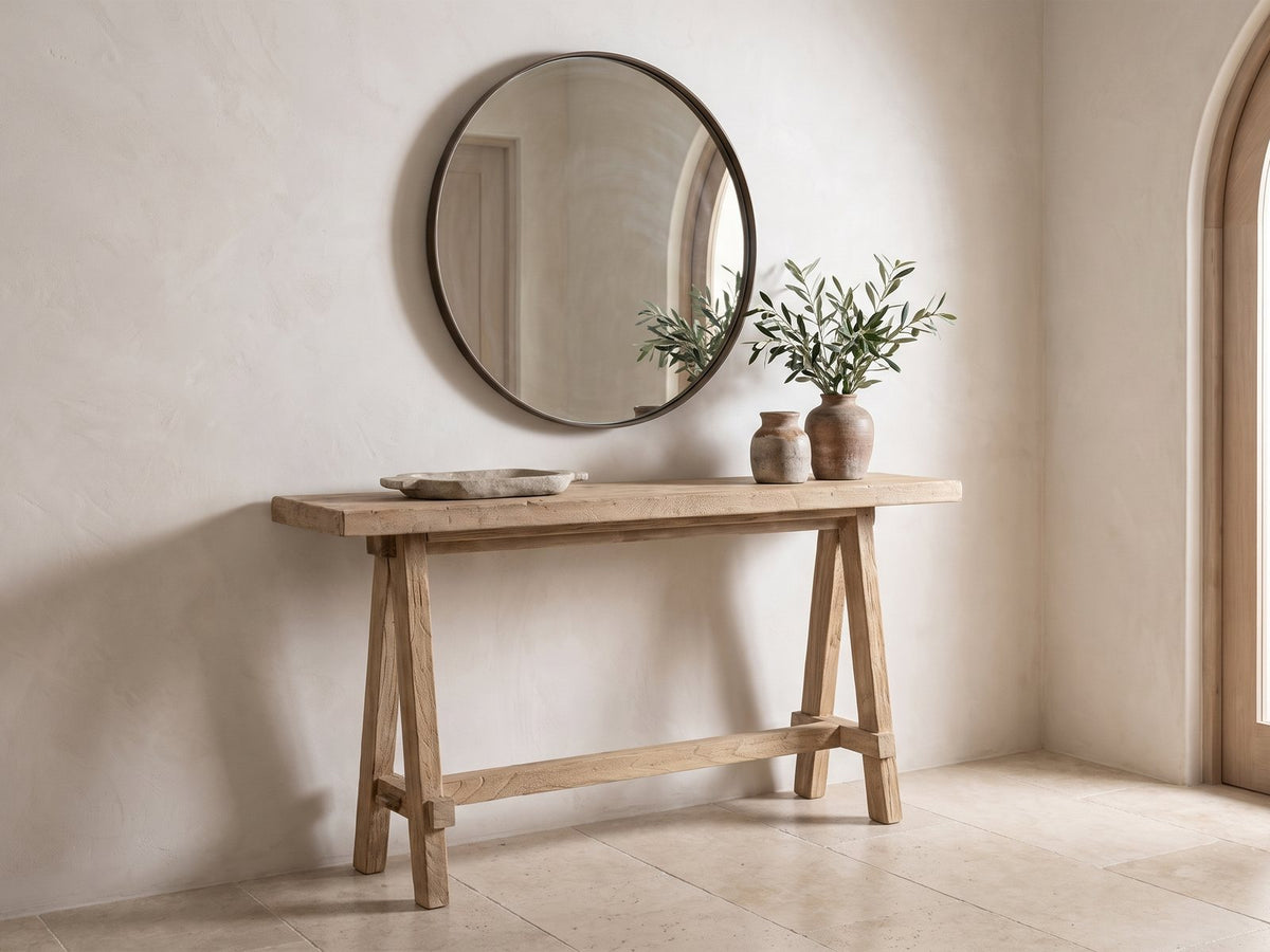 Ginosa Reclaimed Elm Trestle Console Table under a round mirror in a travertine entryway