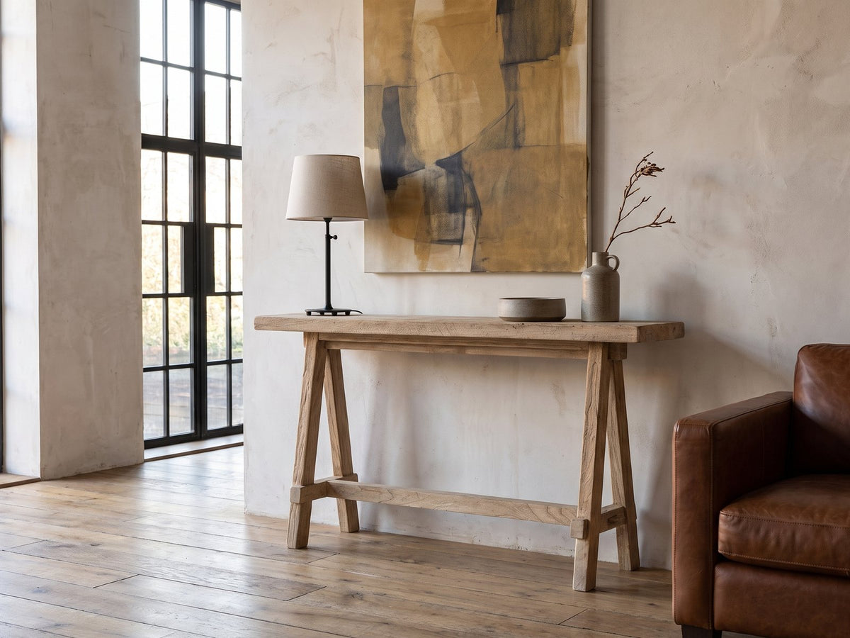Ginosa Reclaimed Elm Trestle Console Table against a plaster wall in an industrial loft