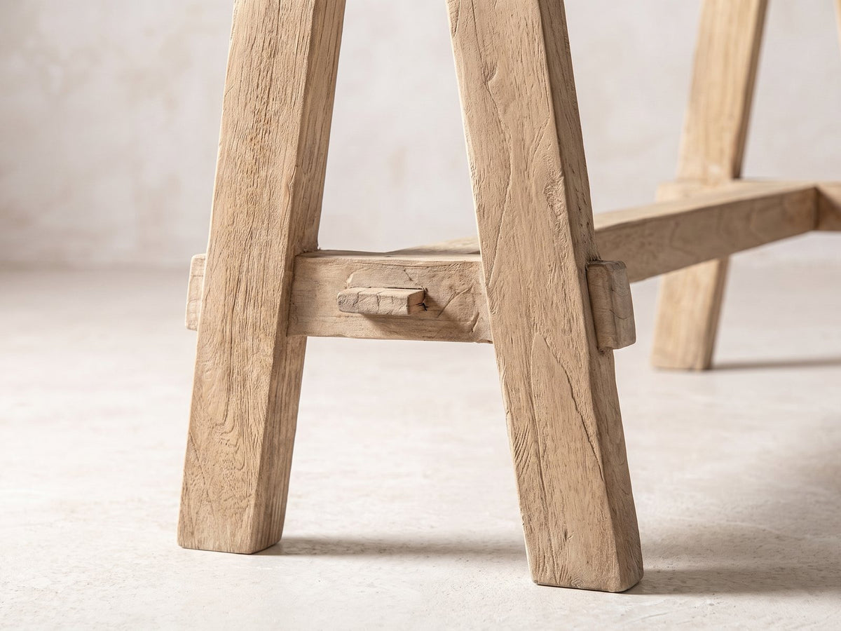 Close-up of the Ginosa Reclaimed Elm Trestle Console Table: the low crossbar of an A-frame trestle, through-tenoned and wedged