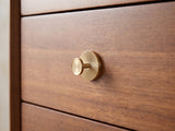 Close-up of the Gorizia 62-Inch Warm Walnut 6-Drawer Dresser: a sunburst-fluted brass knob on a walnut drawer front