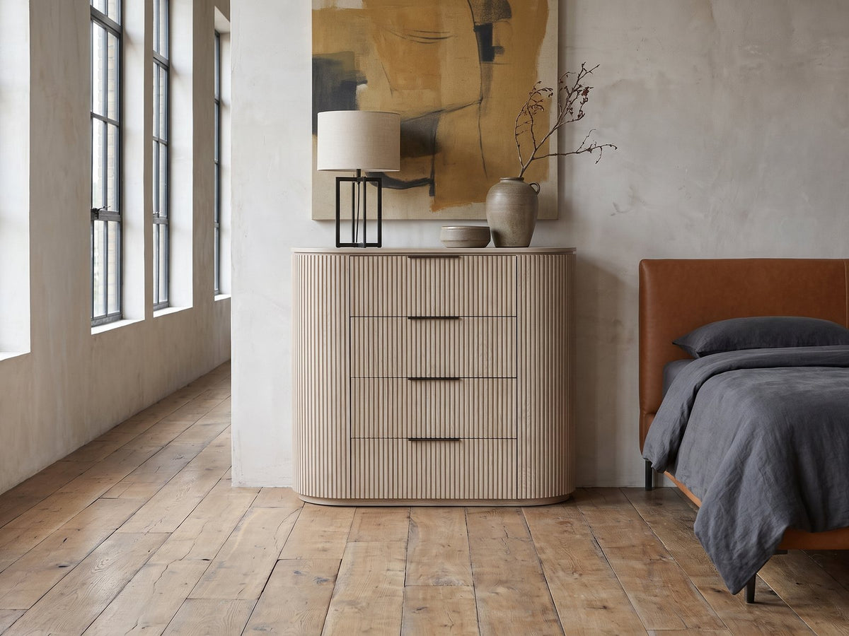Gradisca 50-Inch Light Oak 4-Drawer Chest against a plaster wall in an industrial loft bedroom