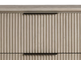 Close-up of the Gradisca 50-Inch Light Oak 4-Drawer Chest: the slim bronze edge pull on a reeded oak drawer front under the oval top
