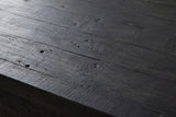 Close-up of black-stained reclaimed pine on the Gravina cabinet: grain, small nail holes and saw marks running to a square edge
