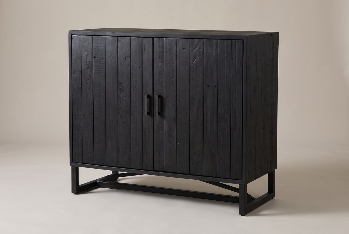 The Gravina two-door cabinet in black-stained reclaimed pine on a black steel base, three-quarter view on a light studio backdrop