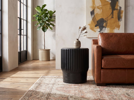 Grottole Black Mango Ribbed Drum Side Table beside a cognac leather armchair in an industrial loft