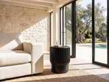 Grottole Black Mango Ribbed Drum Side Table beside a linen sofa in a poolside villa