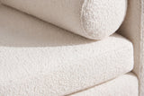 Close-up of the ivory boucle on the Gualdo bench: the round end of a bolster beside the long seat cushion, a fine texture of small tight loops