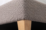 Close-up of the Guardiagrele bed where the taupe gray boucle base meets a tapered natural wood leg