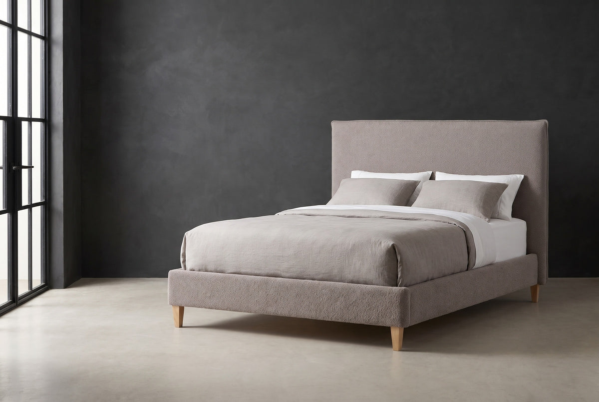 Guardiagrele taupe gray boucle bed against a charcoal limewash wall in a Chicago loft, a tall black steel window at the left