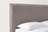 The top corner of the Guardiagrele headboard: a flat taupe boucle panel with a thin flat welt, above a white pillow