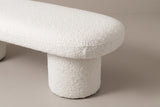 One end of the Gubbio bench: the rounded end of the thick boucle top with its fine seam, overhanging the drum leg below