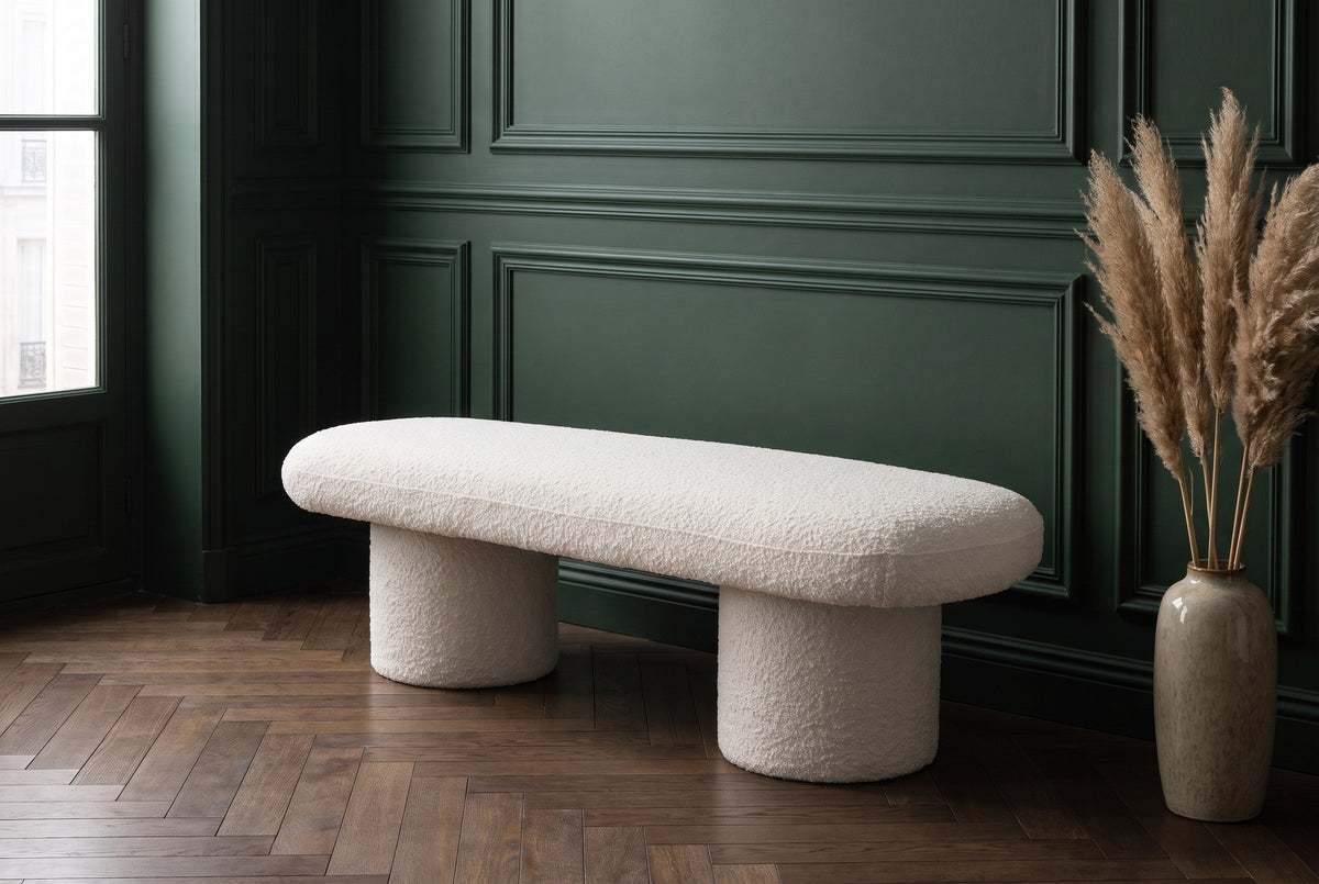 Gubbio ivory boucle bench along a deep green panelled wall in a Paris apartment entry with a herringbone oak floor and a vase of pampas grass