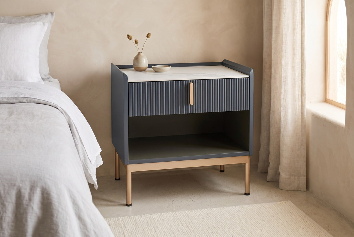 Guspini charcoal fluted nightstand against a sand Roman clay wall in a Scottsdale bedroom with a pale concrete floor and an arched window