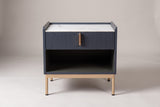 The Guspini nightstand, front view on a light studio backdrop: white stone top, reeded drawer with a gold-tone pull, open cubby and four gold-tone legs