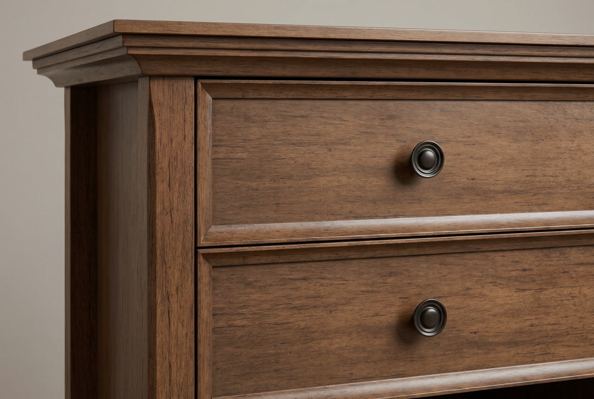 The two drawers of the Iglesias nightstand: framed drawer fronts in aged brown, each with a round antique bronze knob, the crown moulding above