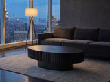 Imola Black Ash Oval Pedestal Coffee Table on a wool rug in front of a velvet sofa in a city penthouse at blue hour